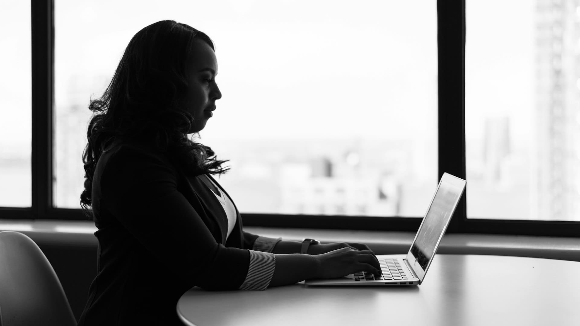 business woman by window in office on her computer
