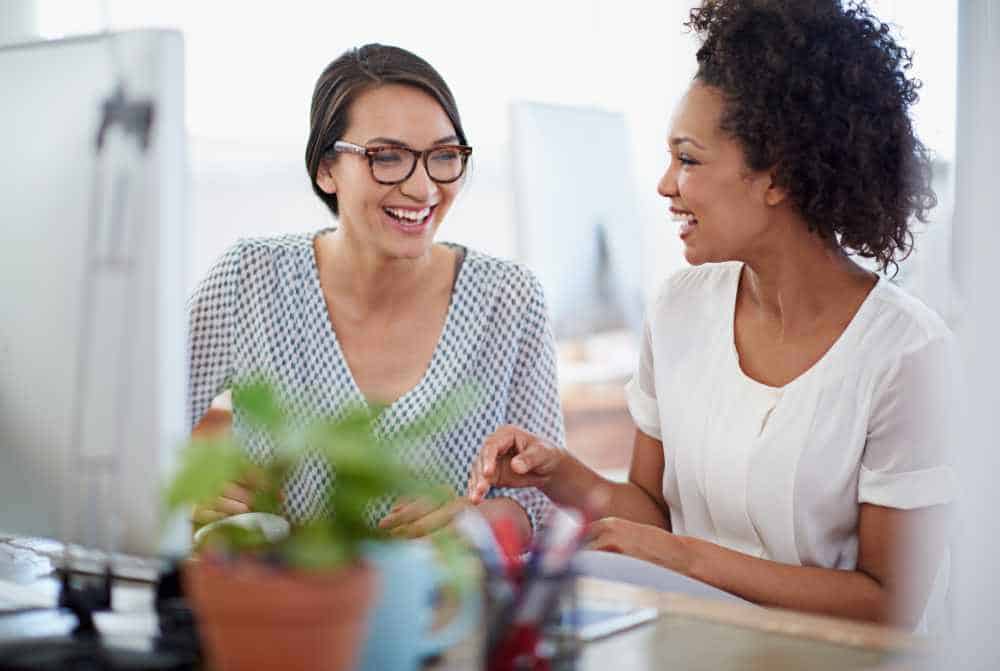 two women in the office at the computer laughing