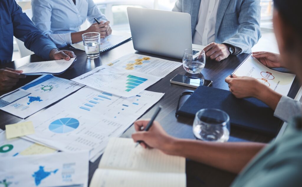 Team collaborating on a website design project—laptops, documents, and notebooks on the table