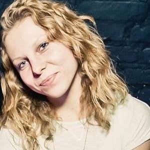 Klaudia Fabian Kobieta z kręconymi blond włosami pozuje przed ceglaną ścianą, podkreślając jej współpracę.