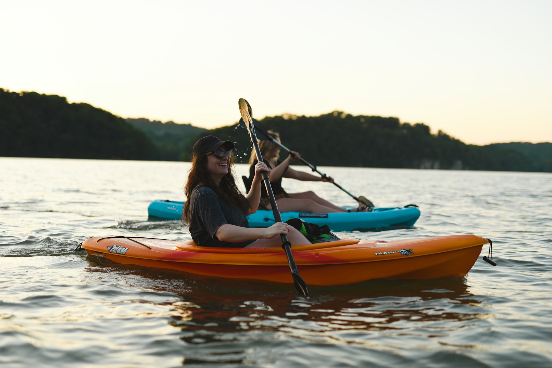 Woman in blue shirt and blue denim jeans riding orange kayak on water during daytime Woman in blue shirt and blue denim jeans riding orange kayak on water during daytime