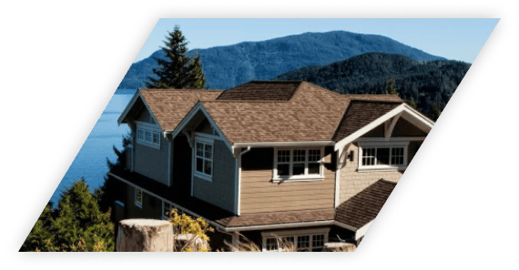 A house with a brown roof located in front of a mountainous landscape.