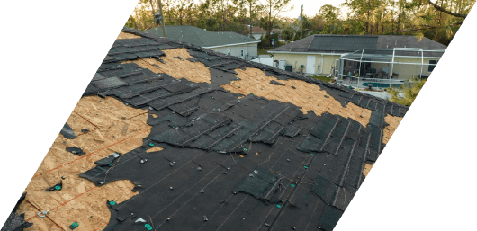 Damaged rooftop with missing shingles after a storm.