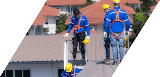 Construction workers wearing safety gear on a residential rooftop.
