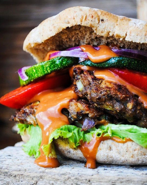 An awesome 2022 burger featuring vegetables and sauce showcased on a wooden table.