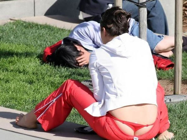 A woman with a whale tail sitting on the grass.