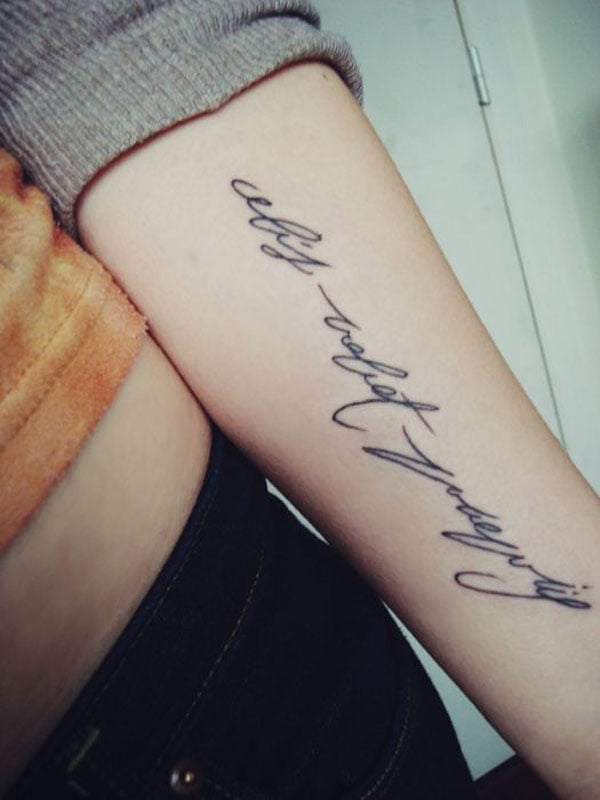 A woman's forearm tattoo with the phrase 'all you need is love'.