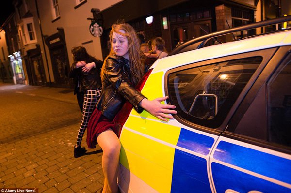 A drunk woman leans on the back of a police car in Britain on New Year's Eve.