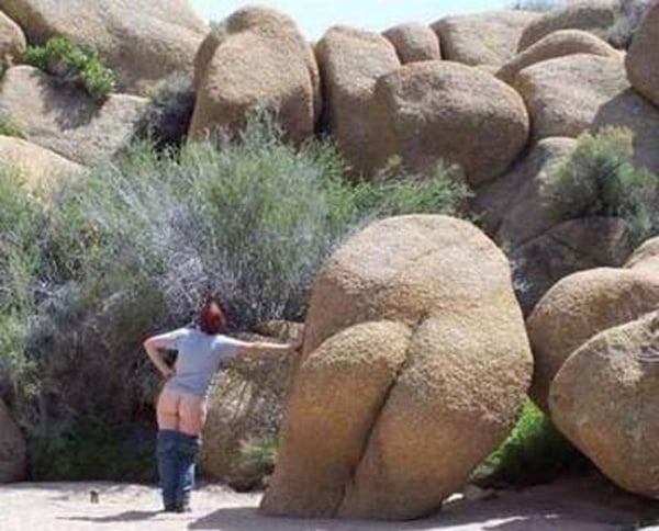 A woman standing next to a large rock, seemingly contemplating the phrase