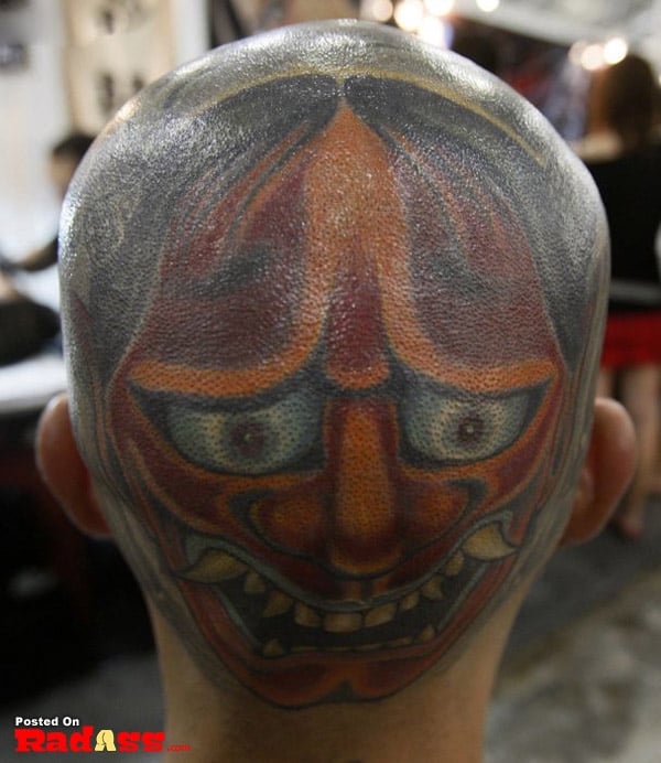 A man's head tattooed with an asian mask showcasing the concept of permanence.