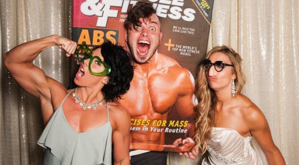 Two women and a man posing for a photo booth while sharing playful banter, expressing