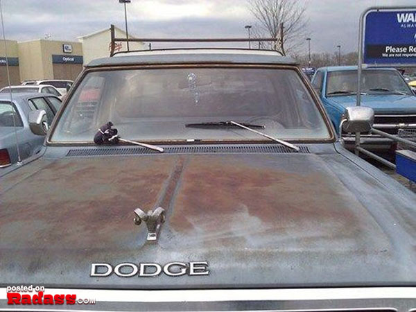 A rusty dodge truck parked in a parking lot, showcasing its redneck aesthetic.