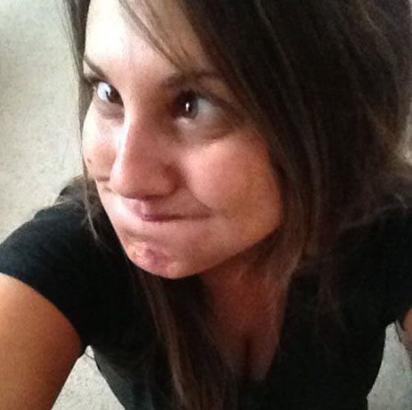 A woman is taking a picture of her face, wondering