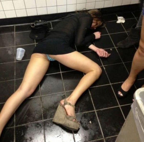 A woman laying on the floor in a bathroom, pondering