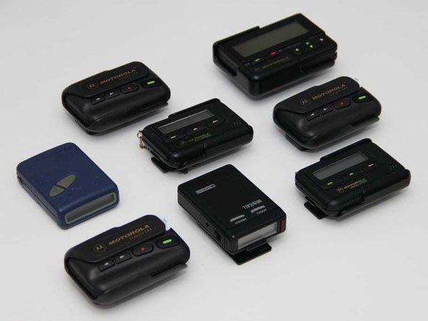 A group of small electronic devices on a white surface. In the past, Beeper Codes were a thing and today you may get a history lesson on how 30-somethings used