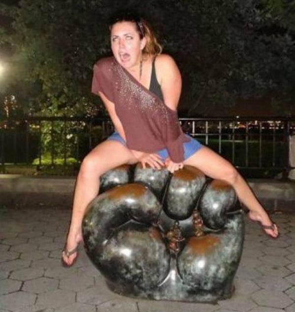 A woman is sitting on top of a large sculpture, pondering her decision not to date but remains intrigued by the possibilities.