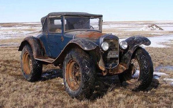 An abandoned off-road vehicle in a field, showcasing the struggle between wants and needs.