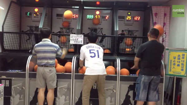 A group of people showcasing sick ass basketball skills on an arcade machine.