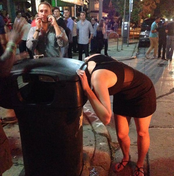 A woman in a black dress leaning over a trash can, contemplating the phrase