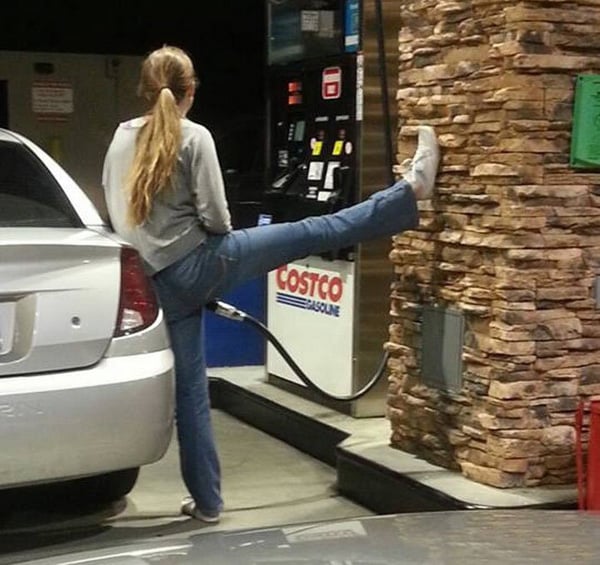 A woman is leaning against a wall at a gas station, contemplating her thoughts with an