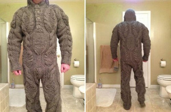 A man in a knitted onesie standing in a bathroom, showcasing his wants over his needs.