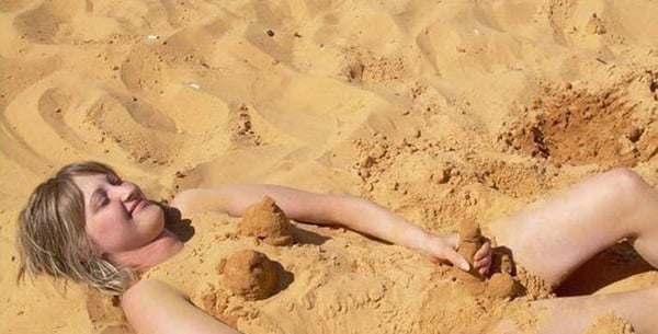 A woman peacefully resting in the sandy embrace of a beach.