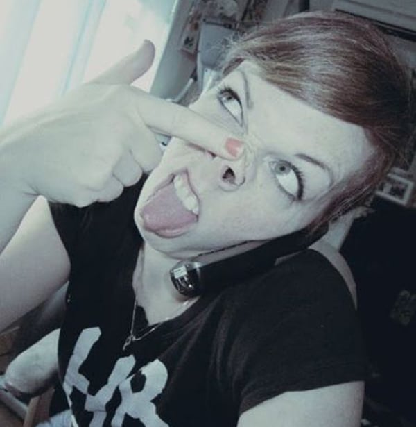 A woman with a tongue sticking out of her nose, signaling