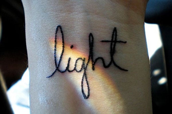 A woman's wrist tattooed with the word light.