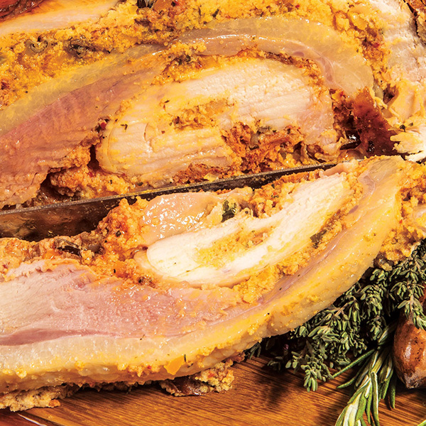 A manly ham adorned with rosemary and thyme displayed on a rustic wooden board.