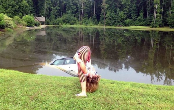 A woman doing a handstand in front of a car, showcasing her impressive athleticism.