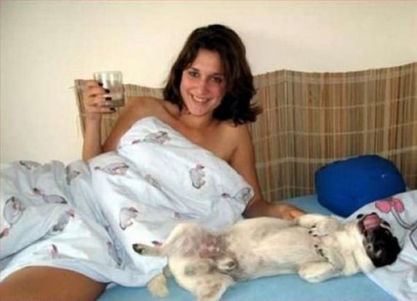 A woman snuggling with a pug on her lap.