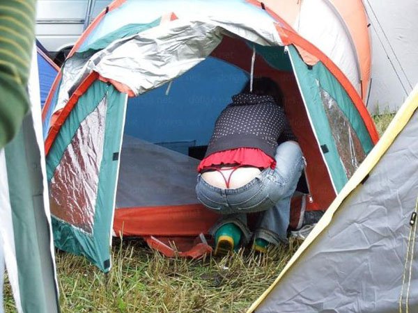 A woman is inserting her pants into a tent, revealing a subtle whale tail.