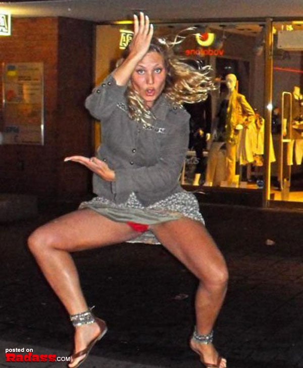 A woman is dancing on the street at night, expressing her carefree spirit and infectious energy.