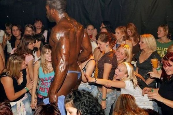 A man standing in the middle of a crowd of people, looking somewhat lonely and lost.