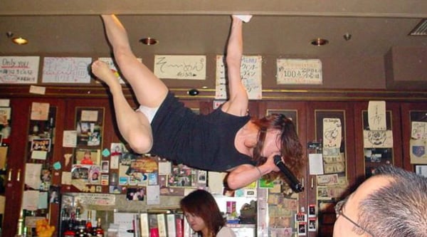 A woman is hanging from the ceiling of a bar, leaving everyone wondering