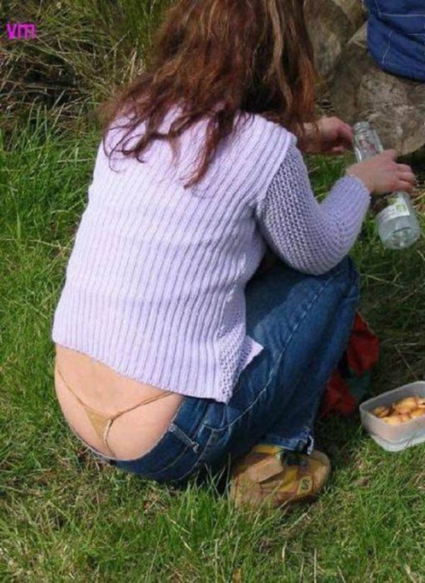 A woman sitting on the grass with a bottle of water, showcasing a whale tail
