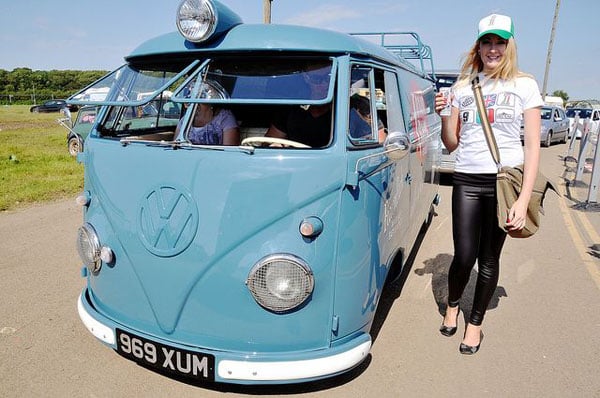 A babe posing with a blue VW bus.