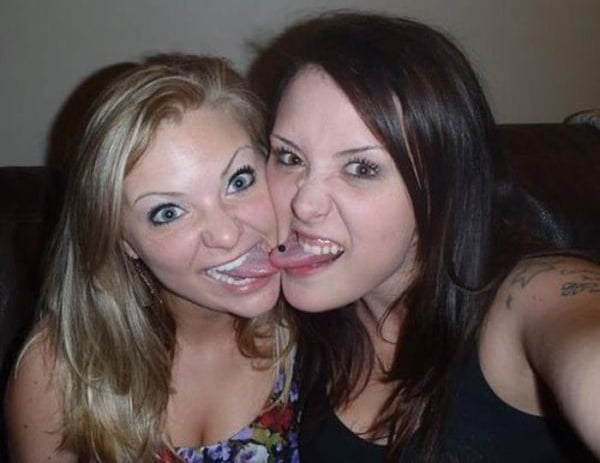 Two women are posing for a picture with their tongues out, conveying a playful