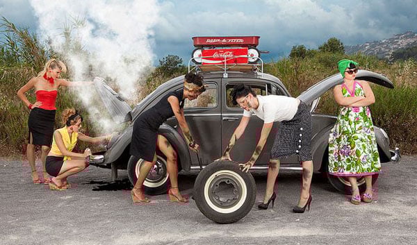A group of babes standing next to an old car.