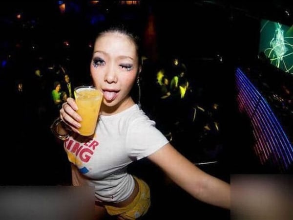 A woman is holding a drink at a nightclub in
