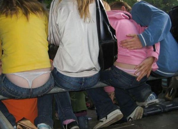 A group of people sitting on a bench with their whale tail showing.