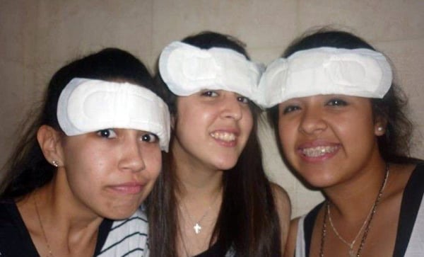 Three girls posing for a picture with bandages on their heads in