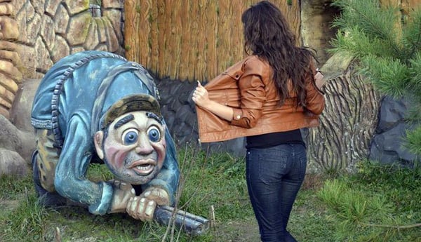 A woman stands next to a statue of an old man, contemplating