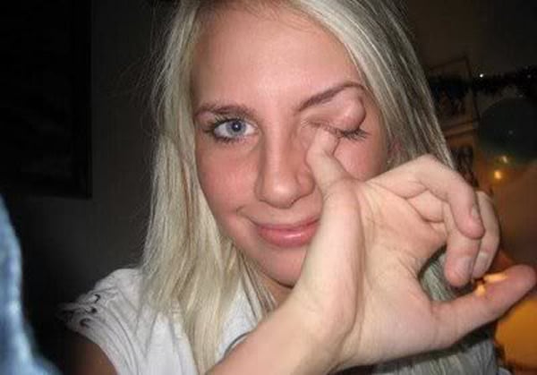 A woman is holding her finger up to her eye, expressing the gesture from