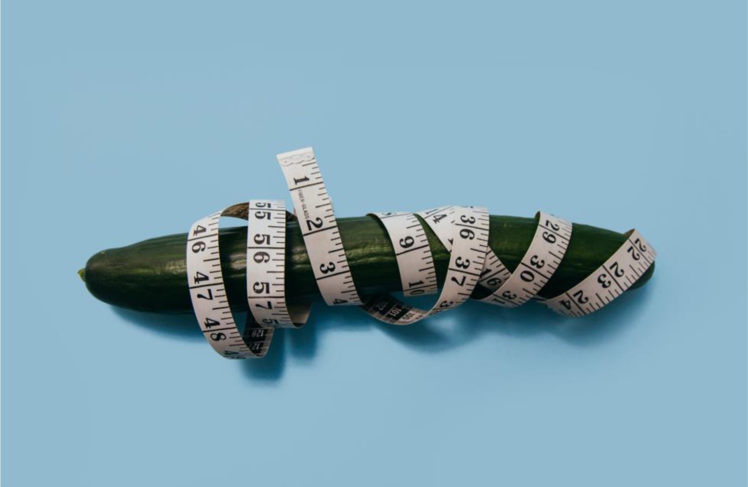 Cucumber, measuring tape, blue background.