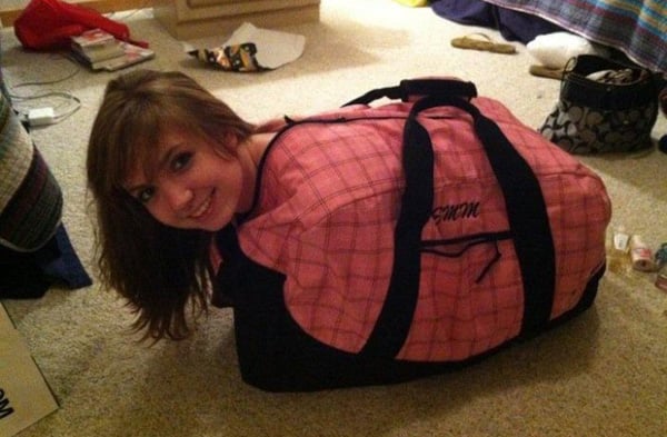 A girl lounging on the floor with a pink duffel bag beside her, contemplating an
