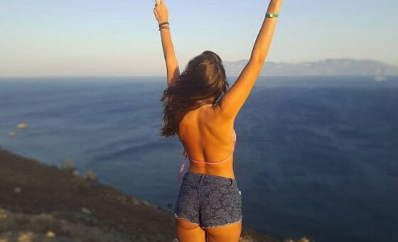 A woman is standing on a cliff overlooking the ocean, experiencing That Friday Feeling.