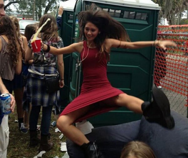 A woman in a red dress jumping on a couch, defying societal expectations.