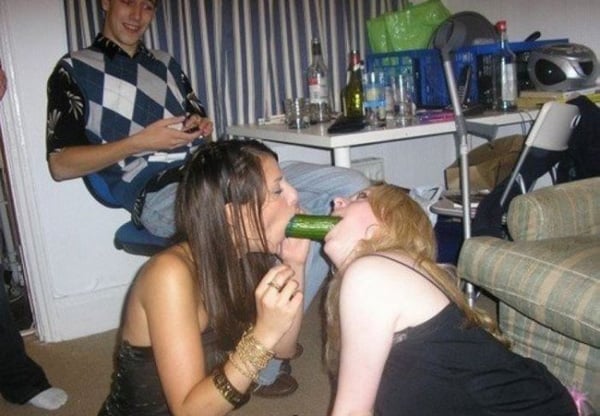 A group of people enjoying a cucumber snack while hanging out in a living room.