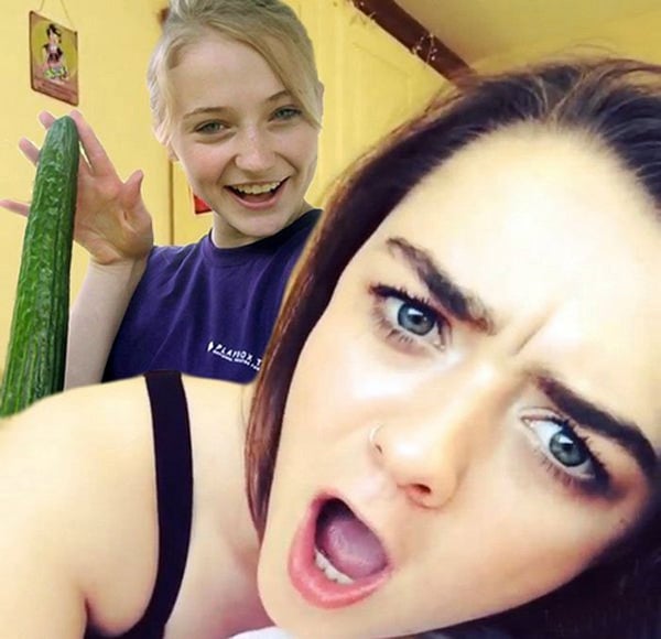 A girl is holding a cucumber and making a face, expressing her reaction to it.